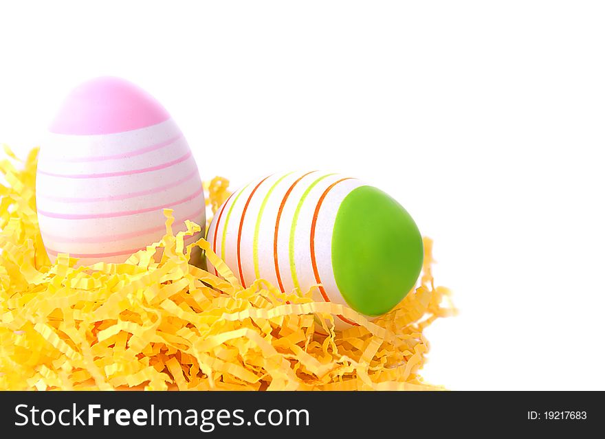 Two easter eggs in yellow nest on white background