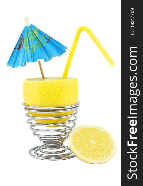 Bright lemon in the metal spiral eggcup with umbrella and straw on the white background. Bright lemon in the metal spiral eggcup with umbrella and straw on the white background