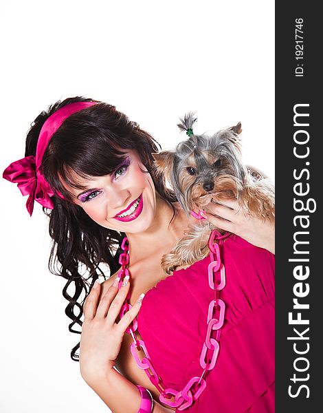 Portrait of beautiful girl with dark long curly hair and vibrant make-up wearing pink satiny ribbon holding small dog on white background. Portrait of beautiful girl with dark long curly hair and vibrant make-up wearing pink satiny ribbon holding small dog on white background