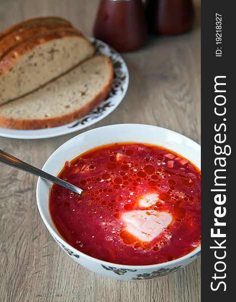 Traditional borscht with beet, meat, potatoes and sour cream, served with grey bread