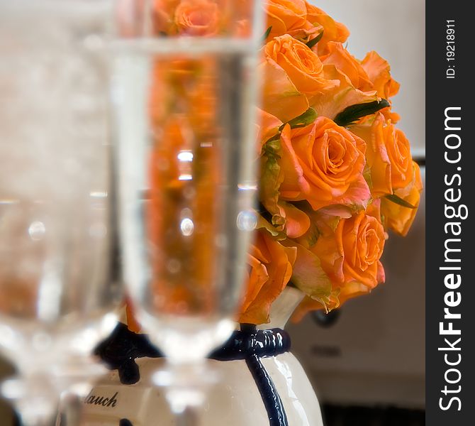 Brides Bouquet - orange roses, and wine glasses in the foreground in the zone blurring. Brides Bouquet - orange roses, and wine glasses in the foreground in the zone blurring