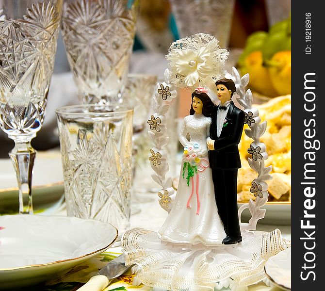 At the wedding table among the wine glasses there is a small figurine - figurine of the bride and groom