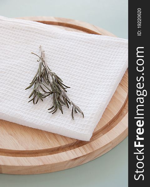 Rosemary on the white towel and round breadboard