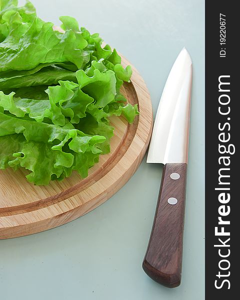 Fresh green salad on the breadboard with knife. Fresh green salad on the breadboard with knife
