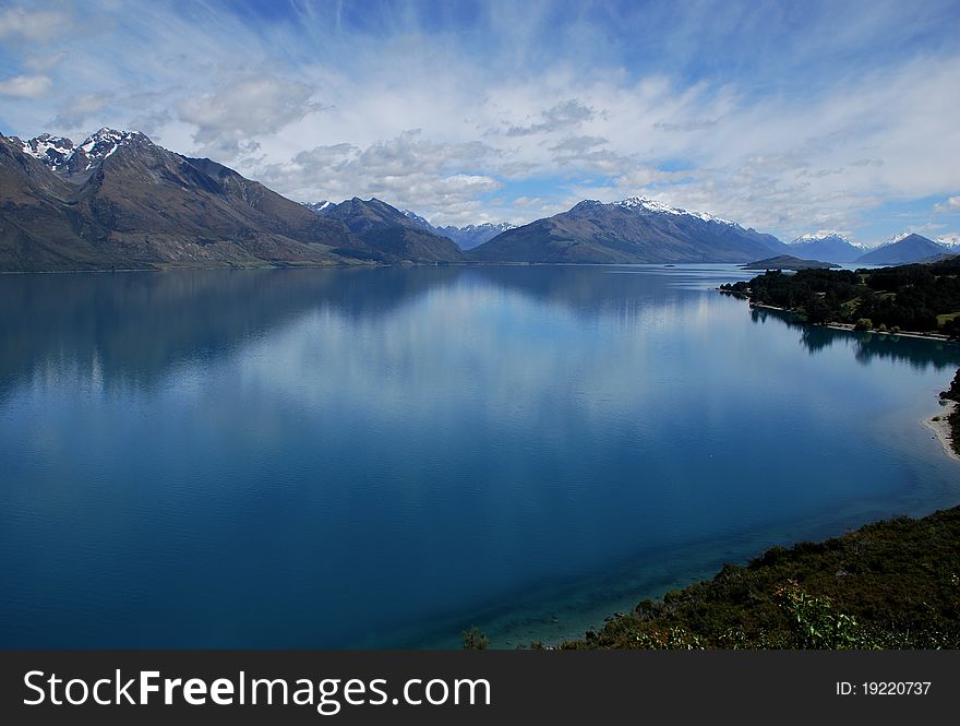A beautiful reflection of the sky is created by a flat lake in Queenstown New Zealand