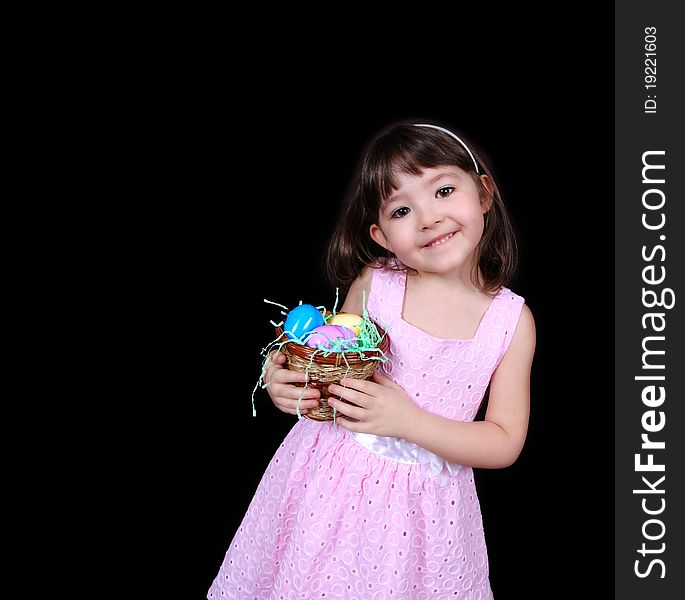 Sweet little girl holding basket of bright easter eggs isolated on black. Sweet little girl holding basket of bright easter eggs isolated on black