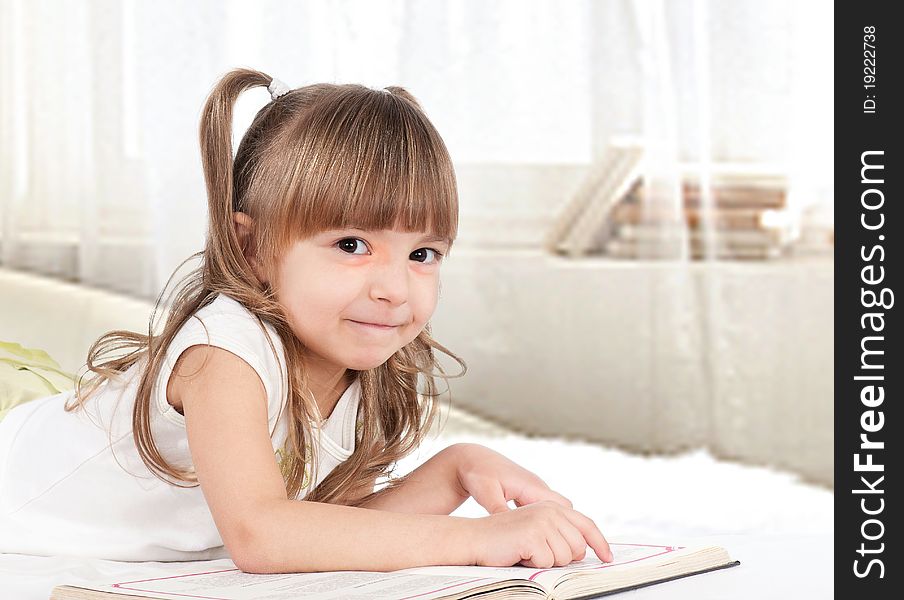 Lovely little girl, reading a book, on the bed. Lovely little girl, reading a book, on the bed