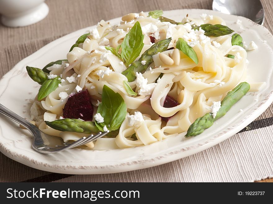 Asparagus and pesto pasta topped with basil and crumbled Cheshire cheese