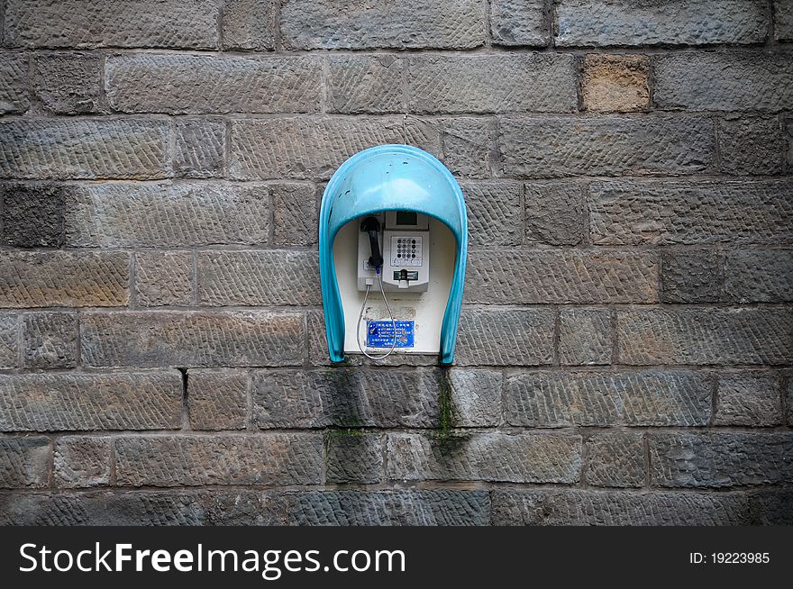 A phone placed on a wall of bricks.