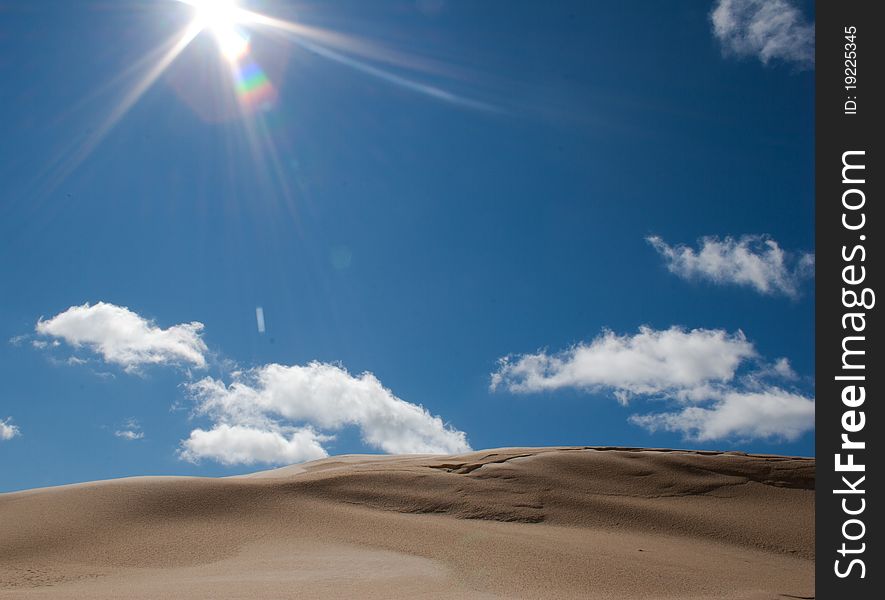 An sand-dune on a sunny day with clouds in a blue sky. An sand-dune on a sunny day with clouds in a blue sky.