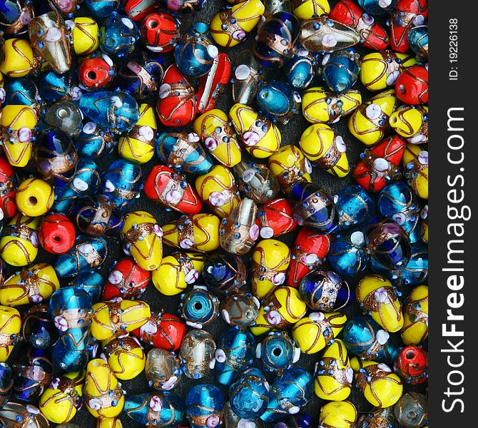 Glass and plastic bright red-yellow-blue costume jewellery on a street market table. Good for background. Glass and plastic bright red-yellow-blue costume jewellery on a street market table. Good for background.