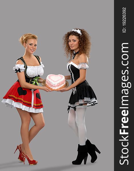 Two pretty girls waitress kept large sweet cake with cream