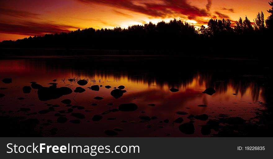 Rocks in a river at sunset. Silhouette on red yellow and orange. Rocks in a river at sunset. Silhouette on red yellow and orange.