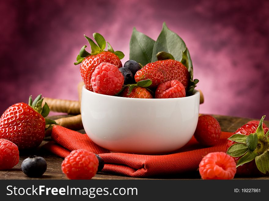 Photo of berries inside a white bowl on wooden table