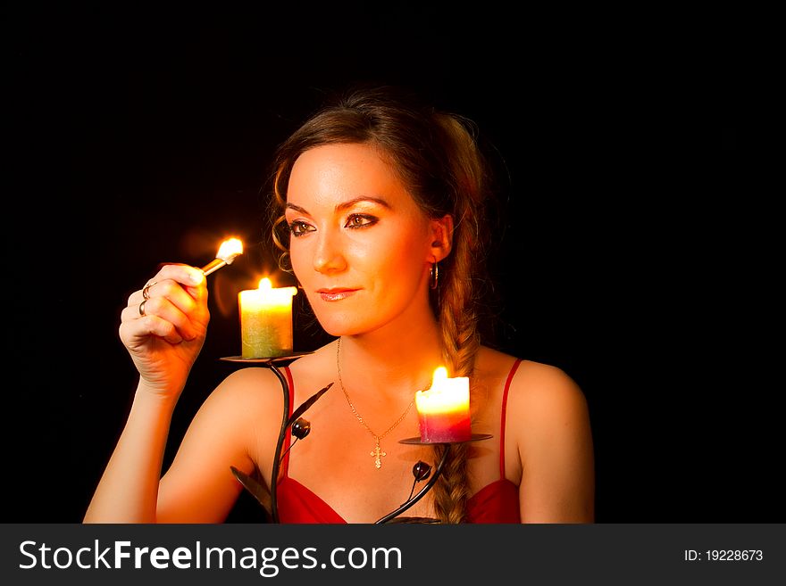 Girl lights a candle at an isolated black background. Girl lights a candle at an isolated black background