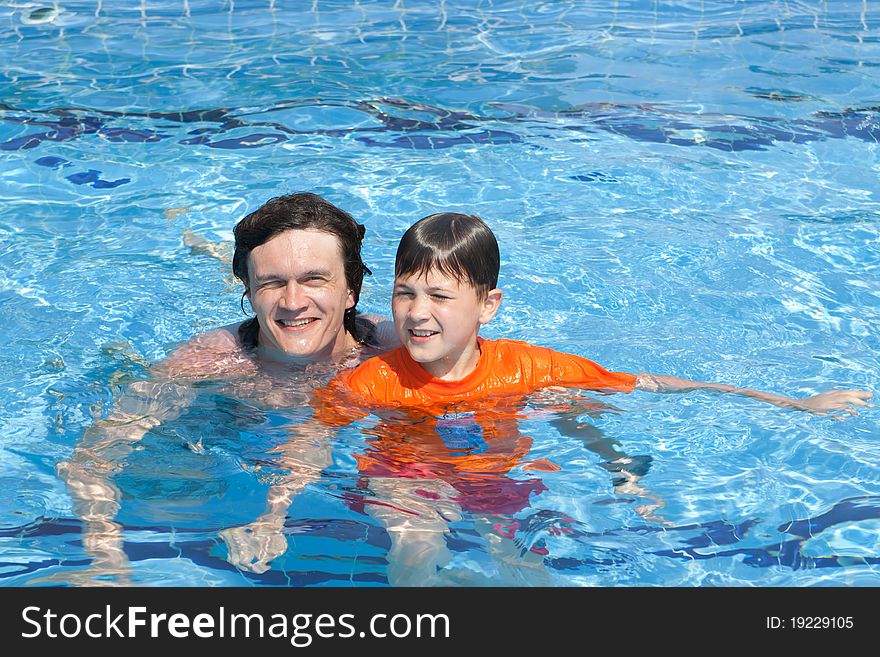 The father and the son swim in pool