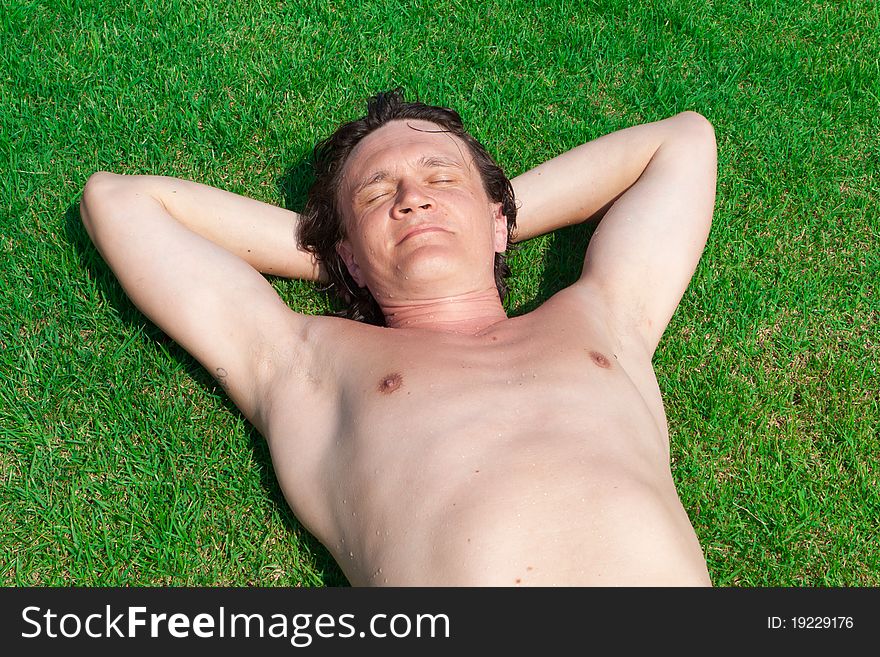 The man lies on a green lawn. The man lies on a green lawn