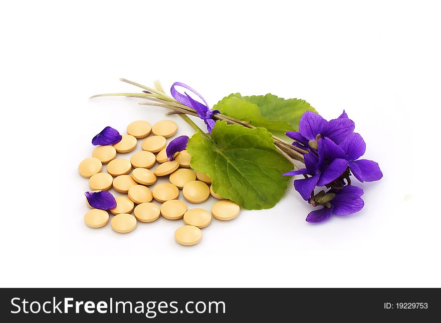 Herbal  pills and flowers on a white background