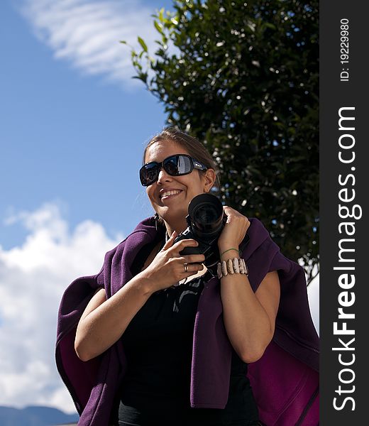 Beautiful girl with sunglasses holding a dslr camera during her vacation. Beautiful girl with sunglasses holding a dslr camera during her vacation