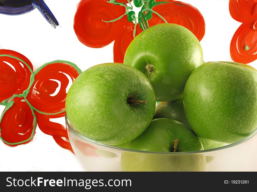 Green apple with flowers in a glass bowl