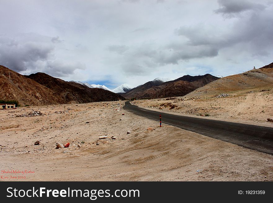 The image is of a solitary road in the high himalayas in ladhak. The image is of a solitary road in the high himalayas in ladhak