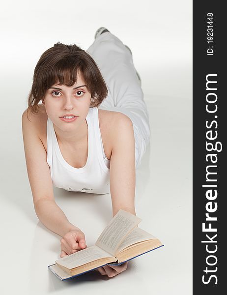 Girl lying on the floor and reads a book, looking straight. Girl lying on the floor and reads a book, looking straight