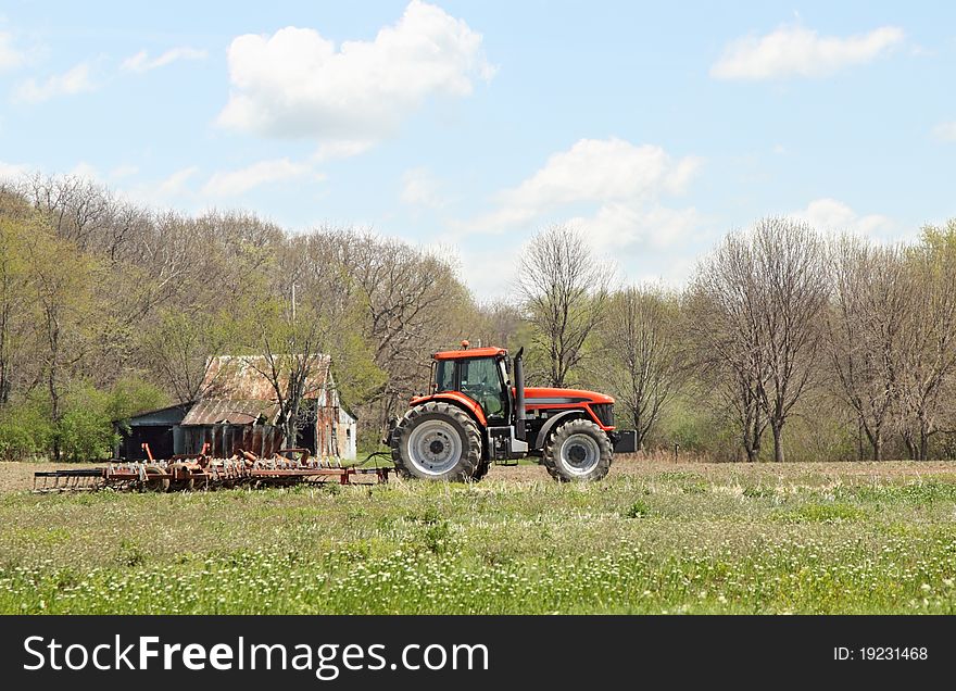 Red tractor pulling a plow in a farm field. Red tractor pulling a plow in a farm field