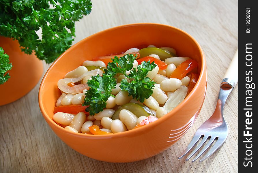 A bowl of stewed beans with vegetables decorated with parsley. A bowl of stewed beans with vegetables decorated with parsley.