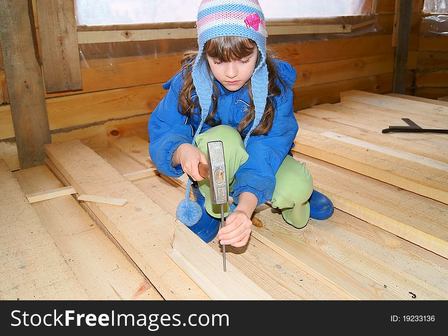 The girl hammers in a nail into a board a hammer