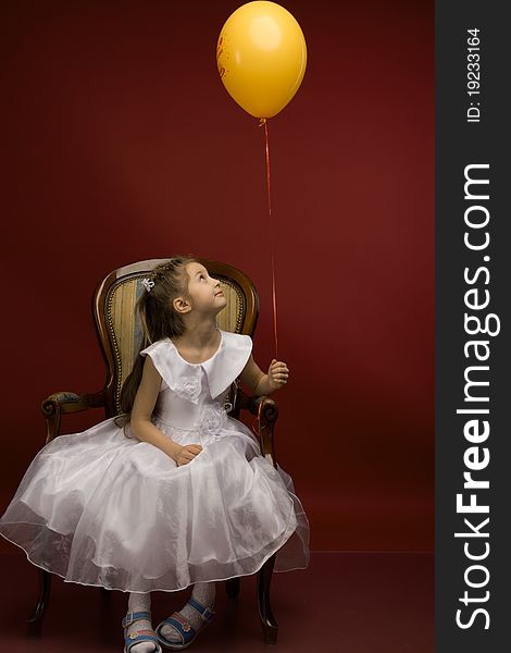 Studio portrait of a young pretty girl sitting on the armchair and with yellow balloon. Studio portrait of a young pretty girl sitting on the armchair and with yellow balloon