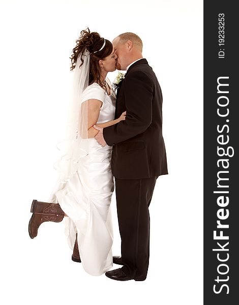 A bride and groom kissing and holding each other.  The bride is holding her foot up with a cowboy boot on. A bride and groom kissing and holding each other.  The bride is holding her foot up with a cowboy boot on.