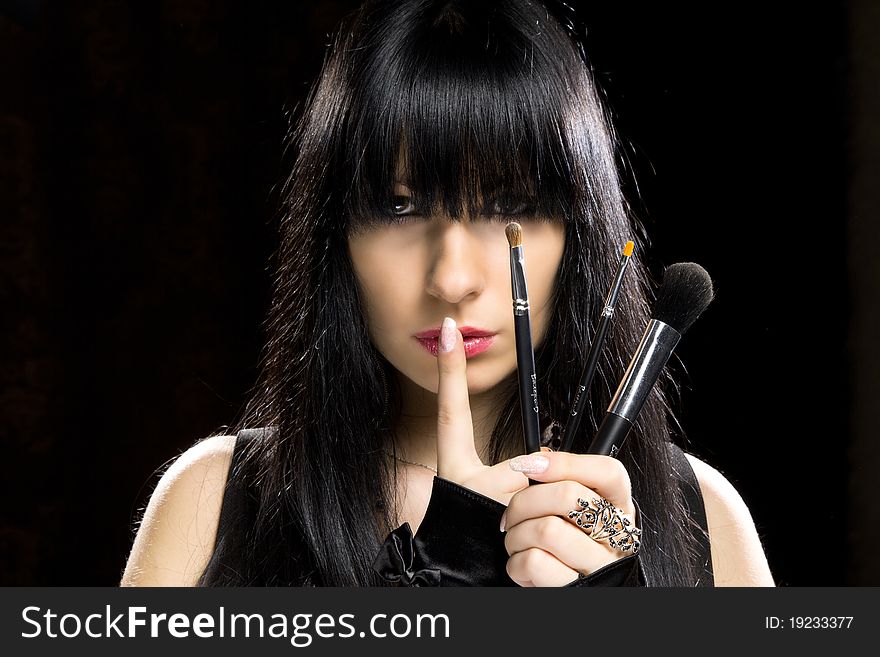 Close-up portrait of a young beautiful brunette girl with long hair and long nails holding brushes. Close-up portrait of a young beautiful brunette girl with long hair and long nails holding brushes