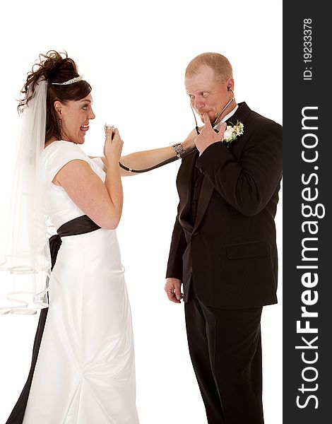 A bride flirting with her groom by playing doctor and talking into her stethoscope. A bride flirting with her groom by playing doctor and talking into her stethoscope.