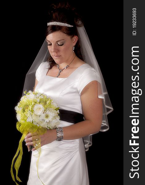 A bride on a black background looking down at her flowers. A bride on a black background looking down at her flowers.