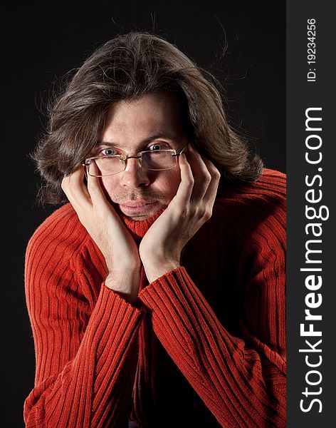 Man with log hair in red sweater and glasses.