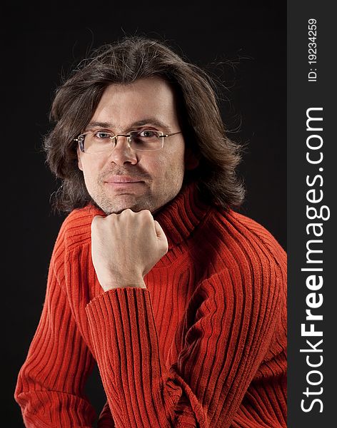 Man with log hair in red sweater and glasses.
