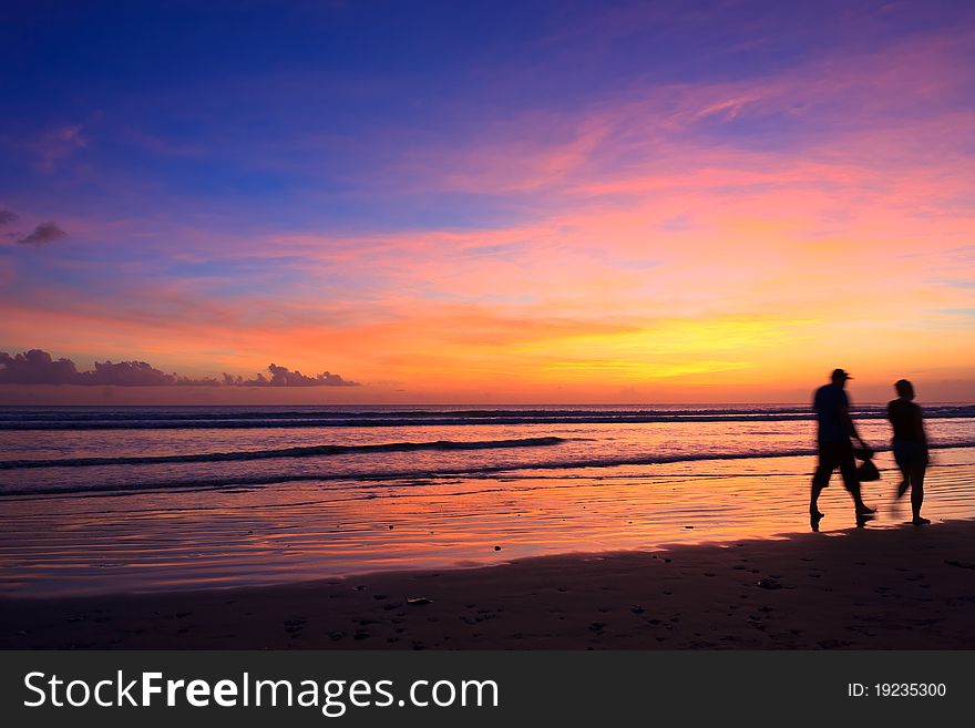 Female and male runners silhouette with a sunset sky and sea