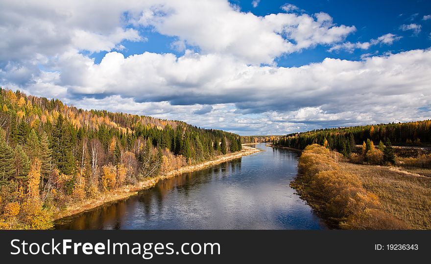 River with green and yellow trees.