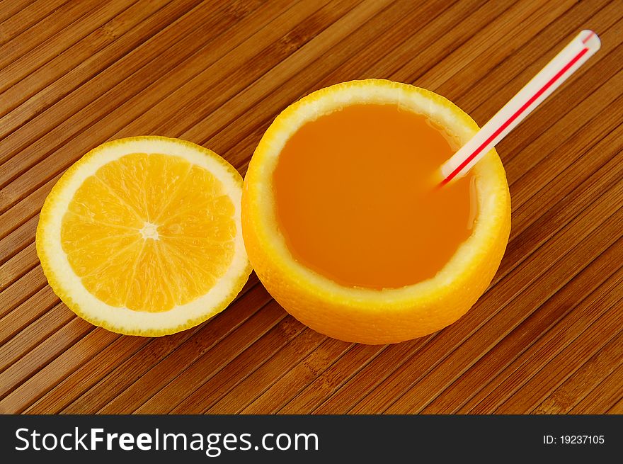Fresh orange juice with straw on a bamboo mat
