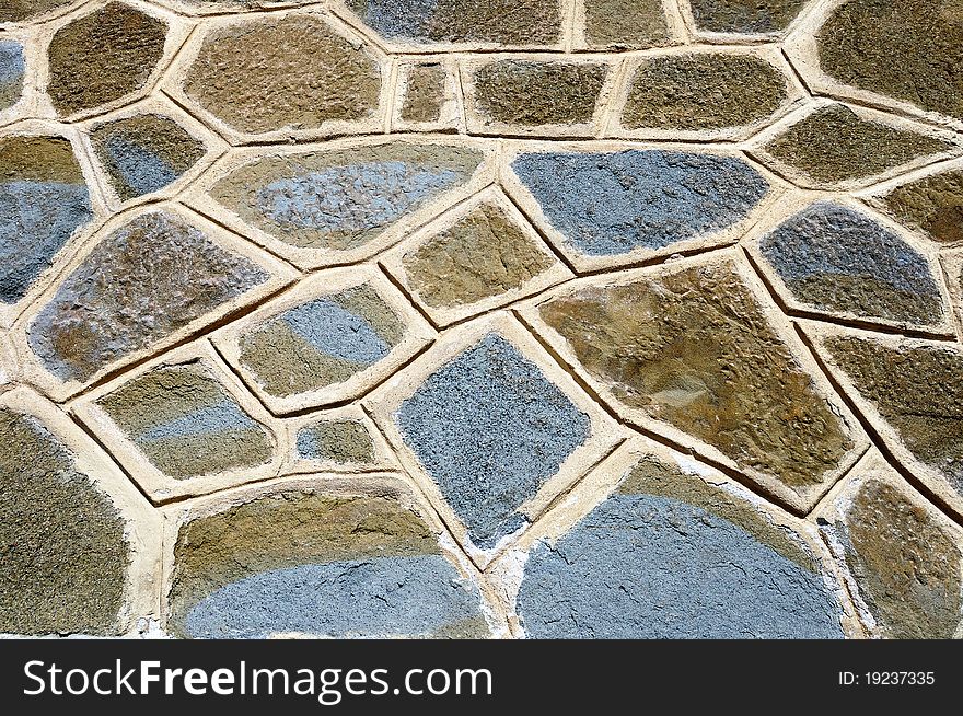 A rough wall made of colored cemented stones. A rough wall made of colored cemented stones