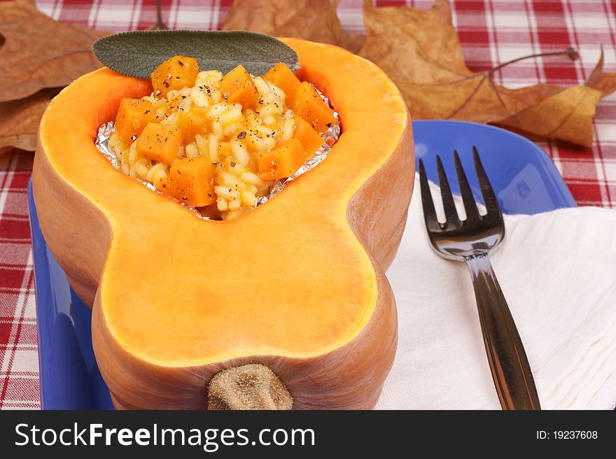 Half pumpkin filled with pumpkin risotto served on a blue plate