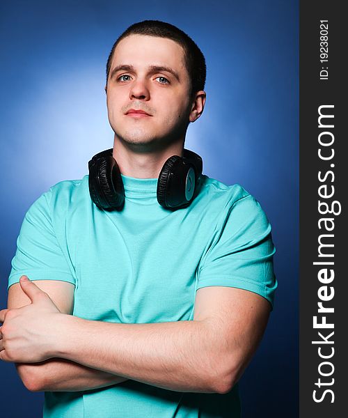 Man with headphones listening music at blue background