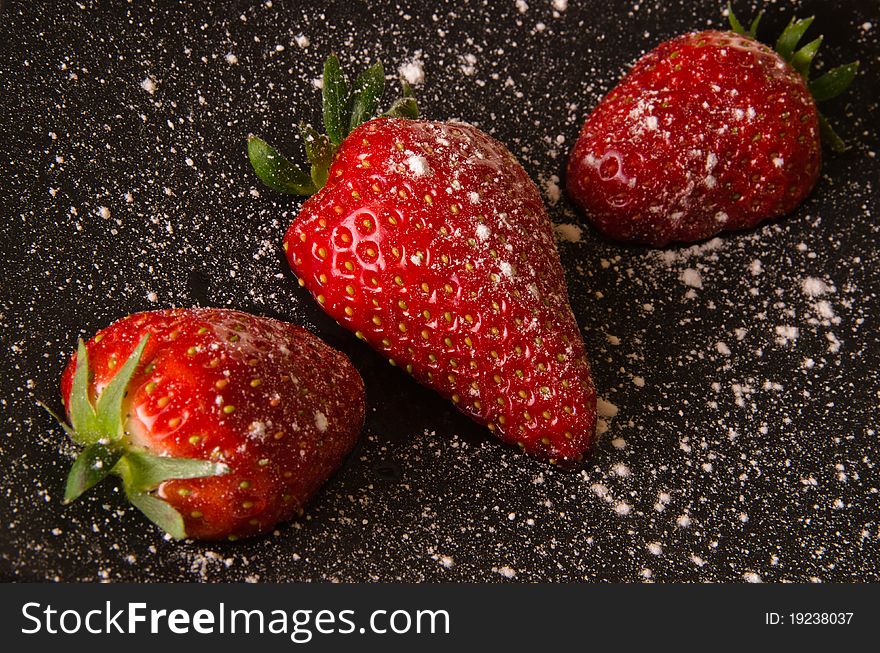 Strawberries cut in half on a plate with icing sugar. Strawberries cut in half on a plate with icing sugar