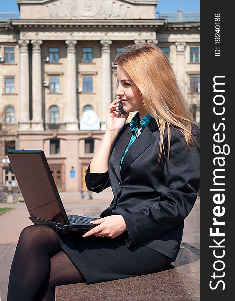 The business woman with a notebook speaks by phone against an old building. The business woman with a notebook speaks by phone against an old building