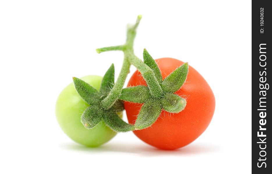 A green and a red cherry tomatoes isolated on a white background. A green and a red cherry tomatoes isolated on a white background