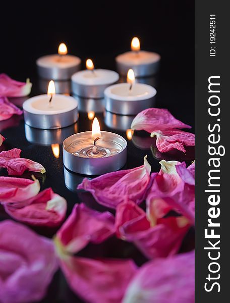 Candles and petals on black background