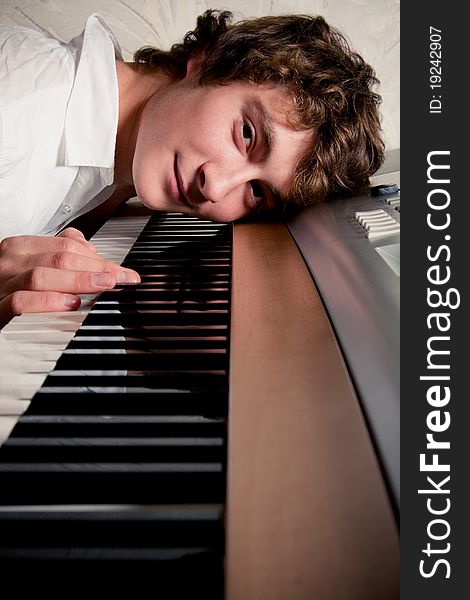 Portrait of a boy lying on a piano keyboard.