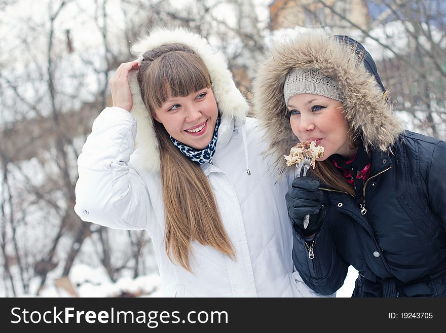 Two girls eating meat in winter outside. Two girls eating meat in winter outside