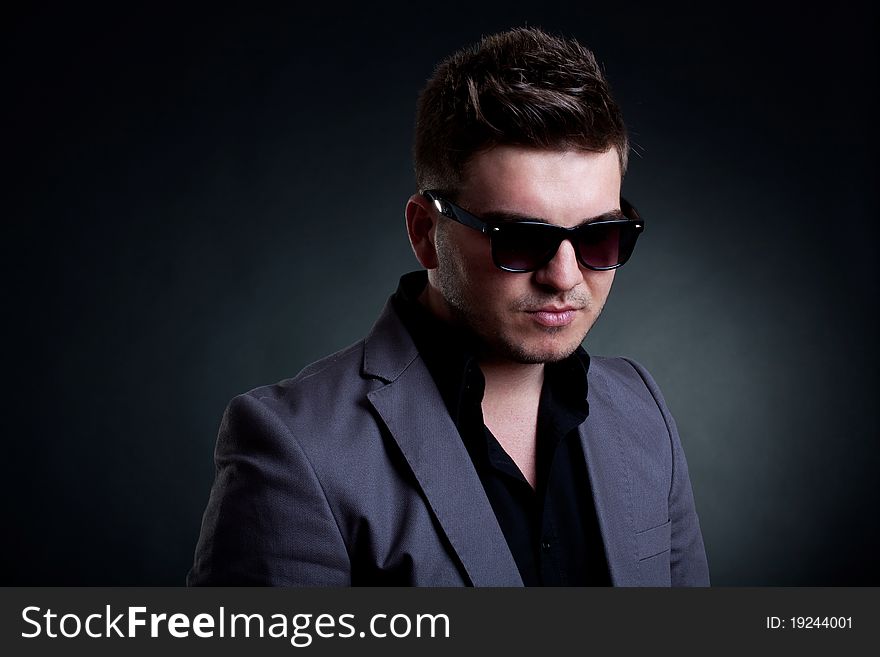 Portrait of young handsome man with sunglasses , over dark background