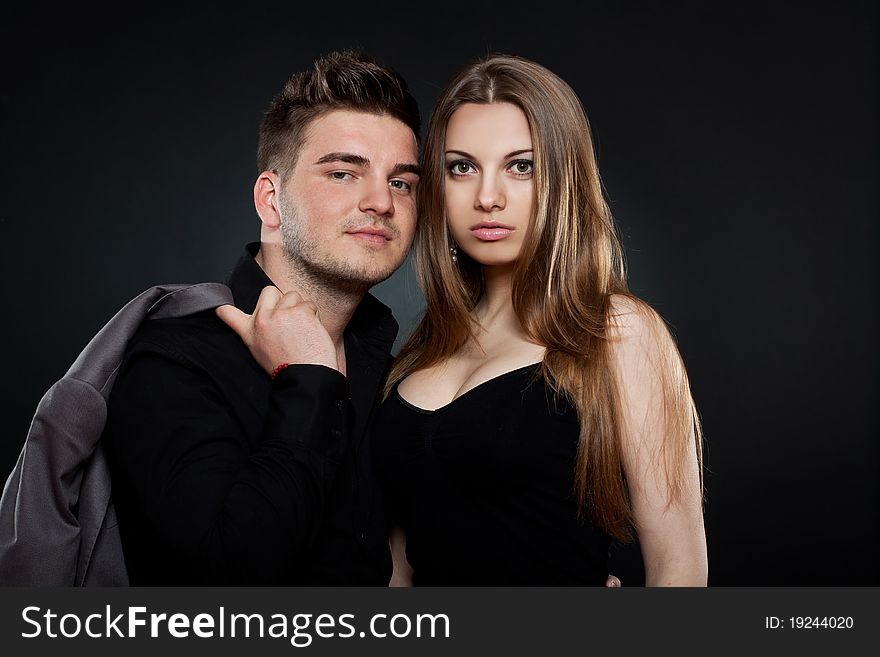 Picture of a young couple standing next to each other on black